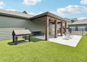 Thumbnail 64 of 88 - a covered patio with a picnic table and chairs in a backyard at The Depot Raymore, MO 64083