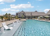 Thumbnail 7 of 88 - a swimming pool with chairs and a building in the background at The Depot Raymore, MO 64083