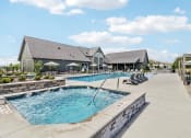 Thumbnail 2 of 88 - a swimming pool with chairs and a building in the background at The Depot in The Depot Raymore, MO 64083