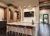 Thumbnail 11 of 18 - A modern kitchen with a bar area and a television mounted on the wall at The Stadler Luxury Apartments, Florida