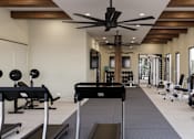 Thumbnail 10 of 18 - A gym with a variety of equipment including treadmills, weights, and a rowing machine at The Stadler Luxury Apartments, Bradenton, FL 34210