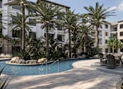 Thumbnail 14 of 18 - A pool surrounded by palm trees and chairs at The Stadler Luxury Apartments, Bradenton, Florida