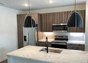 Thumbnail 2 of 18 - A modern kitchen with a marble countertop and stainless steel appliances  at The Stadler Luxury Apartments, Bradenton, Florida