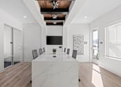 Thumbnail 35 of 36 - A long white table with a plant on it sits in the middle of a room with a wooden ceiling and a chandelier.