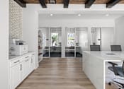 Thumbnail 26 of 36 - A white kitchen with a wooden floor and a white counter.