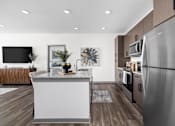 Thumbnail 16 of 36 - A modern kitchen with a stainless steel refrigerator and wooden flooring.