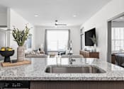 Thumbnail 15 of 36 - A modern kitchen with a granite countertop and a stainless steel sink.