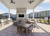 Thumbnail 24 of 36 - A patio with a table and chairs and a stone fireplace.