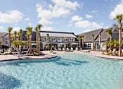 Thumbnail 25 of 36 - A swimming pool surrounded by palm trees and buildings.