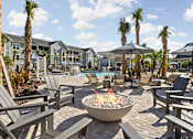 Thumbnail 4 of 36 - A fire pit sits in the middle of a patio surrounded by chairs and umbrellas.