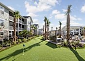 Thumbnail 36 of 36 - A miniature golf course is surrounded by palm trees and a pool.