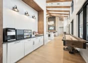 Thumbnail 29 of 53 - a long cafeteria with a long wooden table and a counter with coffee machines at The Garrison Luxury Apartment Homes, Fountain, CO 80817