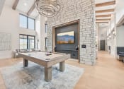 Thumbnail 32 of 53 - a pool table in a living room with a stone fireplace at The Garrison Luxury Apartment Homes, Fountain