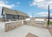 Thumbnail 37 of 53 - the backyard has an outdoor kitchen with a grill and a bar at The Garrison Luxury Apartment Homes, Fountain, CO 80817