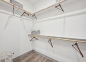 Thumbnail 15 of 53 - a white closet with hangers on the wall and a basket on the floor at The Garrison Luxury Apartment Homes, Fountain Colorado