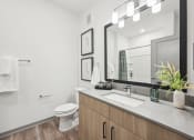Thumbnail 18 of 53 - a bathroom with a sink and a toilet and a mirror at The Garrison Luxury Apartment Homes, Fountain, CO 80817