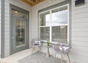 Thumbnail 20 of 53 - the front porch of a house with two chairs and a table at The Garrison Luxury Apartment Homes, Colorado