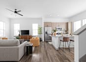 Thumbnail 2 of 68 - A modern living room with a grey couch, a black television, and a kitchen area in the background.