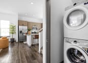 Thumbnail 57 of 68 - A modern laundry room with a washing machine and a view into a kitchen.