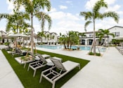 Thumbnail 51 of 68 - A pool surrounded by palm trees and lounge chairs.
