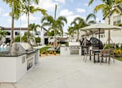 Thumbnail 49 of 68 - A patio with a grill and chairs under a canopy.