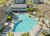 Thumbnail 72 of 83 - A large swimming pool surrounded by lounge chairs and palm trees. at Junction Apartments in Rockledge, FL