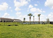 Thumbnail 71 of 83 - A grassy field with palm trees and a building in the background. at Junction Apartments in Rockledge, FL