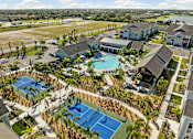 Thumbnail 7 of 83 - A large building complex with a tennis court in the foreground. at Junction Apartments in Rockledge, FL