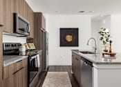 Thumbnail 3 of 59 - A modern kitchen with a dark wood finish. at The Levi Luxury Apartments, McDonough, GA