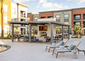 Thumbnail 105 of 108 - A patio with chairs and a table in front of apartment buildings.