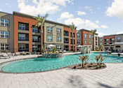 Thumbnail 98 of 108 - A swimming pool surrounded by palm trees and lounge chairs in front of apartment buildings.