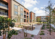 Thumbnail 3 of 108 - A modern apartment complex with a courtyard and trees.