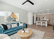 Thumbnail 12 of 108 - a living room with a blue couch and a kitchen in the background at The Maddox Luxury Apartment Homes, Buckeye  