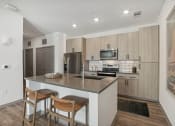 Thumbnail 7 of 108 - a kitchen with a large island with two stools in front of a counter top at The Maddox Luxury Apartment Homes, Buckeye, 85326  