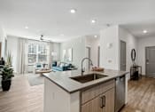 Thumbnail 47 of 108 - an open kitchen and living room with a large window and a sink at The Maddox Luxury Apartment Homes, Buckeye, AZ  