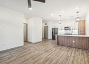 Thumbnail 65 of 108 - a kitchen and living room with white walls and wood floors at The Maddox Luxury Apartment Homes, Buckeye, AZ  