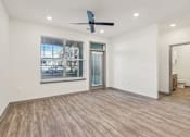 Thumbnail 68 of 108 - an empty living room with a large window and a ceiling fan at The Maddox Luxury Apartment Homes, Buckeye  