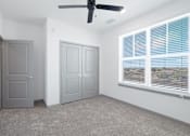 Thumbnail 74 of 108 - an empty room with a large window and a ceiling fan at The Maddox Luxury Apartment Homes, Buckeye, AZ 85326  