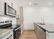 Thumbnail 80 of 108 - an empty kitchen with stainless steel appliances and black counter tops at The Maddox Luxury Apartment Homes, Buckeye Arizona  