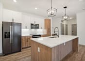 Thumbnail 64 of 108 - a kitchen with a large island and a stainless steel refrigerator at The Maddox Luxury Apartment Homes, Buckeye, AZ 85326  