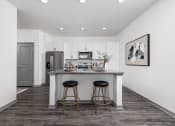 Thumbnail 4 of 38 - a kitchen with a island and stools in a living room at Upland Flats, Colorado Springs, CO, 80922