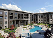 Thumbnail 1 of 4 - A large building with a pool in front.