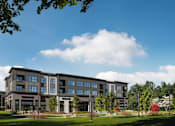 Thumbnail 4 of 4 - A large, modern building with a grassy front yard and trees.