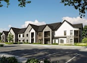 Thumbnail 2 of 4 - A large white building with a black roof is surrounded by a parking lot.