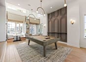 Thumbnail 11 of 61 - A pool table is in the middle of a room with a brown carpet at Verity Luxury Apartments, Florida 32960