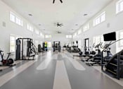 Thumbnail 17 of 61 - A spacious gym with a variety of exercise equipment and a person working out at Verity Luxury Apartments, Florida