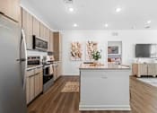 Thumbnail 46 of 61 - A modern kitchen with wooden cabinets and a large island at Verity Luxury Apartments, Vero Beach, FL 32960