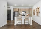 Thumbnail 59 of 61 - A kitchen with a refrigerator, oven, and a counter with two chairs at Verity Luxury Apartments, Florida 32960