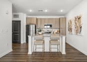 Thumbnail 2 of 61 - A kitchen with a white island and two chairs at Verity Luxury Apartments, Florida 32960