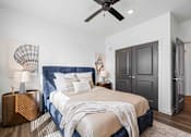 Thumbnail 51 of 61 - A bedroom with a bed, a ceiling fan, and a wooden nightstand at Verity Luxury Apartments, Florida